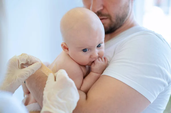 戴着无菌手套的医护人员在婴儿皮肤上的注射部位涂上胶粘剂 — 图库照片
