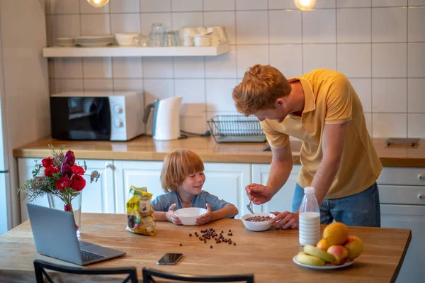 家で朝だ 幼い息子のために朝食を作る若い父親 — ストック写真