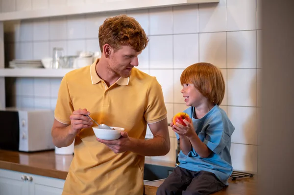 ２人で かわいい子供と彼の父親は朝食を食べて話して — ストック写真