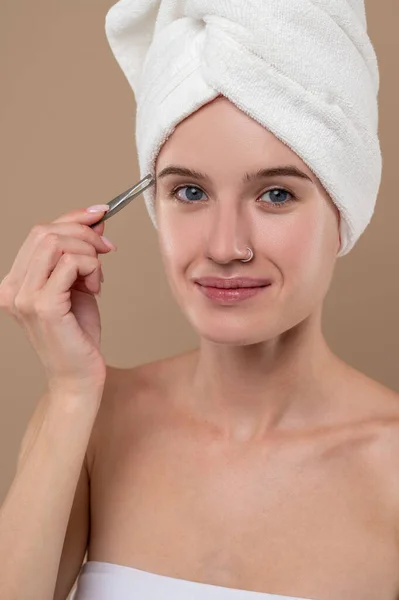 Beauty tricks. Young girl with towel on head making eyebrows