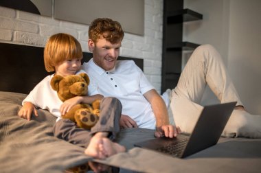 Uyumadan önce. Baba ve oğul yatıp uyumadan önce internette bir şeyler izliyorlar.