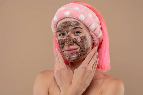 Skin care. Pink-haired girl with a chocolate mask on her face