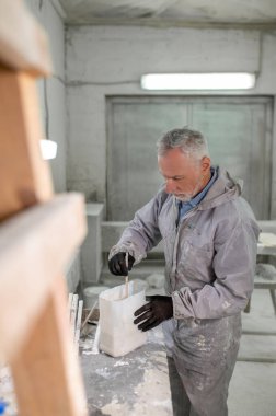 Ahşap. Koruyucu giysili bir adam odun için boya hazırlıyor.