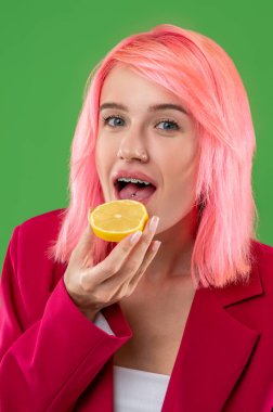 Dili delinen ve limon dilimini açık ağzının önünde tutan bir kızın portresi.