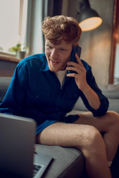 Call from work. A young ginger man talking on the phone and looking involved