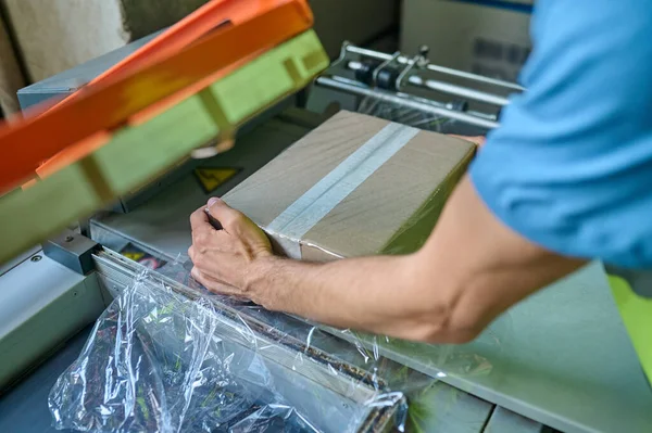 用玻璃纸包装机包裹纸板箱的熟练工人的剪下来的照片 — 图库照片