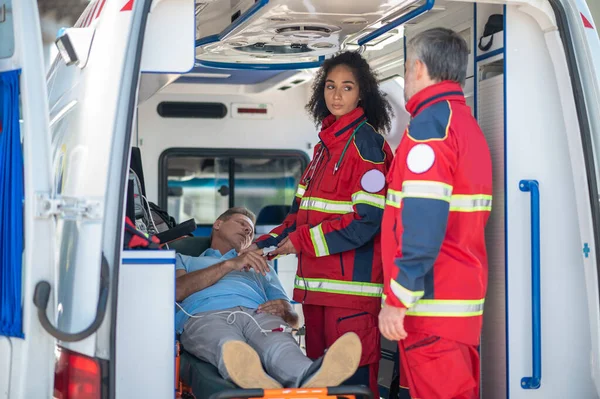 病気の男の血中酸素濃度を測定しながら 彼女の同僚を見て深刻な救急車 — ストック写真