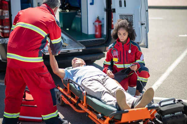 Sanitäterinnen Wickeln Die Blutdruckmanschette Den Arm Des Bewusstlosen Mannes Während — Stockfoto