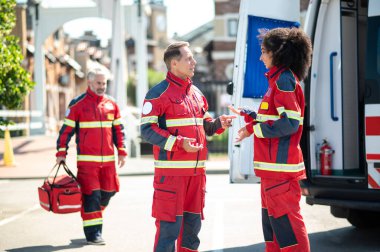 Gülümseyen genç bayan sağlık görevlisi, bir ambulans doktorunun daha gelmesini beklerken meslektaşıyla konuşuyor.