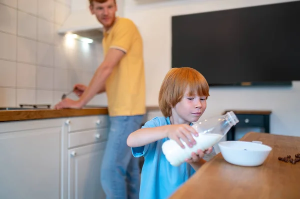 朝食の時間だ 瓶から皿にミルクを注ぐ小さな男の子 — ストック写真