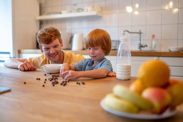 朝食前に遊ぶ 父と息子は朝食前に台所で一緒に時間を過ごす — ストック写真
