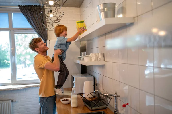 Morning at home. Dad and son in thre kitchen getting ready for breakfast
