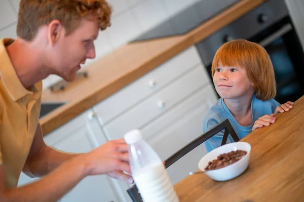 朝食だ 息子の皿に牛乳を注ぐ男 — ストック写真