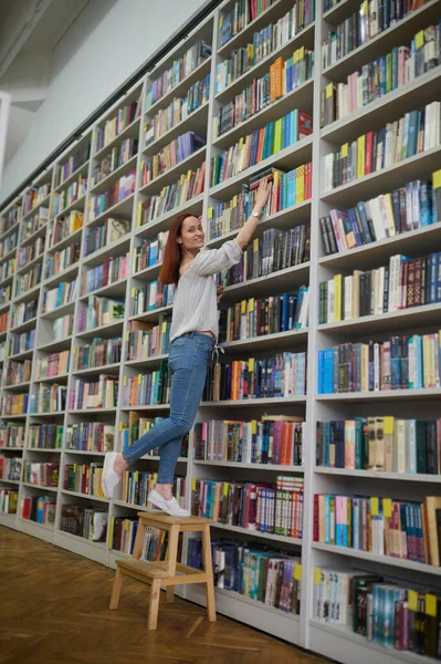 在找一本书年轻的图书管理员在书架上找一本书 — 图库照片