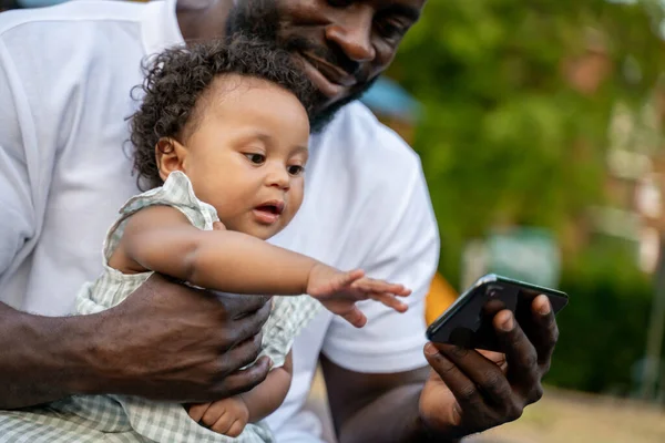 Roztomilé Dítě Sedící Klíně Svého Šťastného Otce Sahá Svém Smartphonu — Stock fotografie