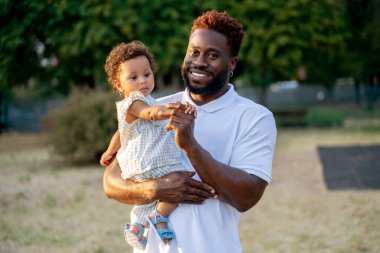 Gülümseyen yakışıklı adam kucağında küçük sevimli bir çocuk ve ona bakıyor.