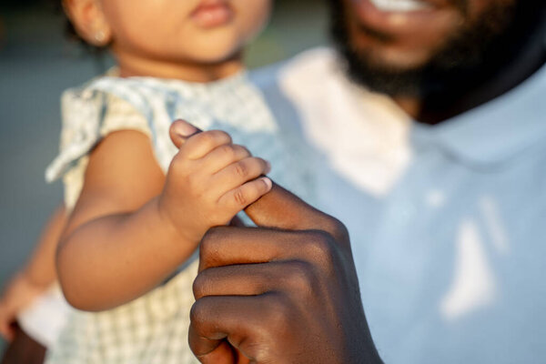 Cropped photo of a smiling bearded African American man holding his child in the arms