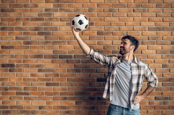 Улыбаясь Молодой Кавказский Футболист Смотрит Футбольный Мяч Поднятой Руке — стоковое фото