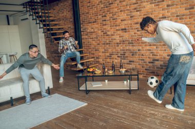 Amatör futbol maçında bir şişe birayla arkadaşlarına tezahürat yapan neşeli adam.