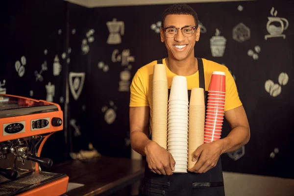 Sonriendo Contento Joven Trabajador Cafetería Sosteniendo Una Pila Tazas Papel — Foto de Stock