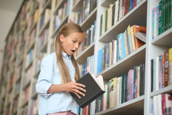 在找一本书可爱的女孩在学校图书馆里找一本书 — 图库照片