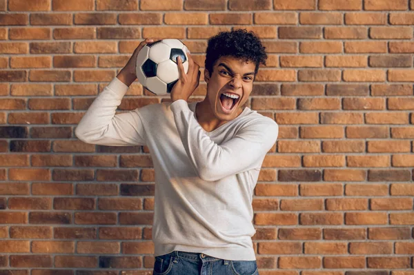 Агрессивный Спортивный Молодой Человек Игровым Мячом Руке Позирует Камеры Помещении — стоковое фото