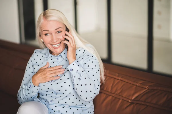 Zadzwoń Mnie Blondynka Dojrzała Kobieta Rozmawia Przez Telefon Siedząc Kanapie — Zdjęcie stockowe