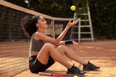 Tenis kortundaki tatlı kız. Tenis kortunda oturan koyu renk saçlı tatlı bir kız.