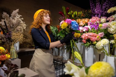 Güzel bir çiçekçi. Çiçekçi dükkanındaki kızıl, genç kadın romantik ve mutlu görünüyor.