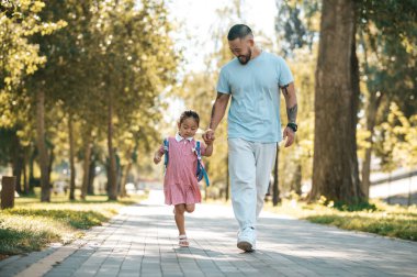 - Aile. Baba ve kızı parkta el ele yürüyorlar.