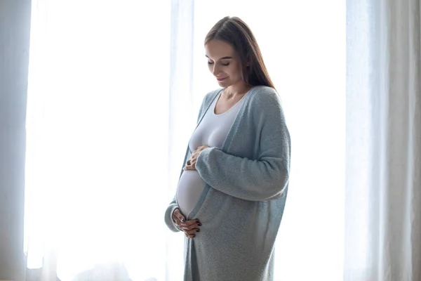 予想してた 窓の近くに立つ長髪の妊婦 — ストック写真