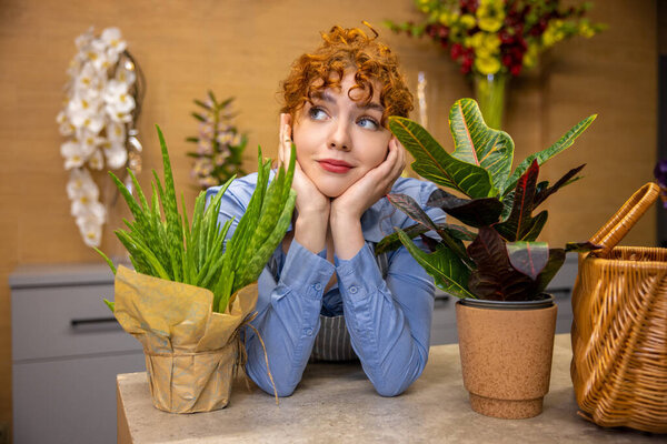 Flower shop. Ginger young florist in a flower shop