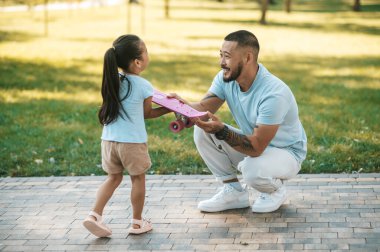 Mutlu bir yolculuk. Parkta kaykay süren sevimli küçük bir kız.
