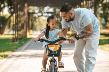 İlk bisiklet. Genç baba çocuğuna bisiklet sürmeyi öğretiyor.