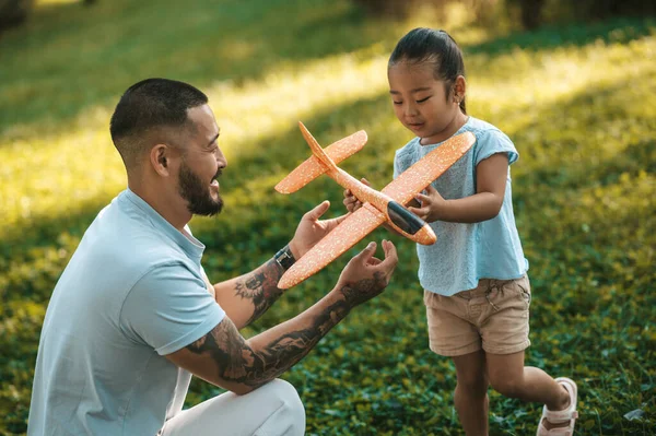 Toy plane. Young man showing his kid how to play with the toy plane