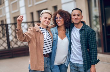 Gülümseyen mutlu genç adam kameraya poz veriyor iki güzel genç bayanla