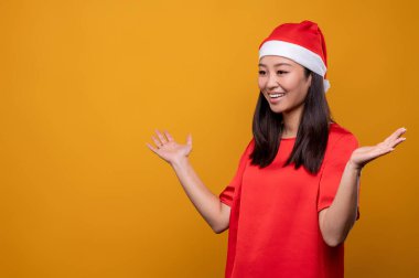 Keyfin yerinde. Kırmızı Noel Baba şapkalı tatlı genç bir kadın mutlu ve eğleniyor.