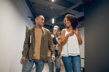 Koridorda onun yanında yürürken meslektaşına gülümseyen neşeli kadın ofis çalışanı.