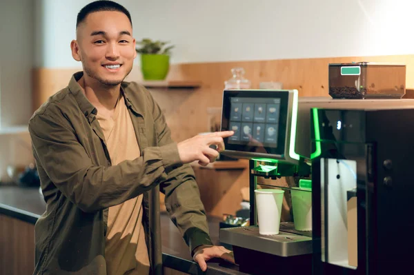 Gülümseyen Neşeli Bir Gencin Belden Yukarı Portresi Kahve Makinesine Dokunuyor — Stok fotoğraf