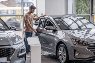 Bir araba galerisinde. Araba galerisinde araba seçen genç bir adam.