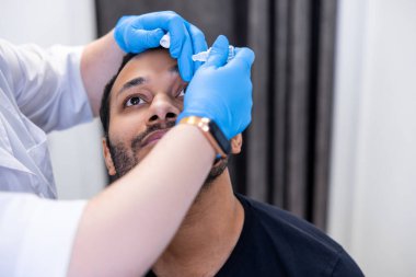 Göz tedavisi. Göz doktoru hastaların gözlerine göz damlası damlatıyor.