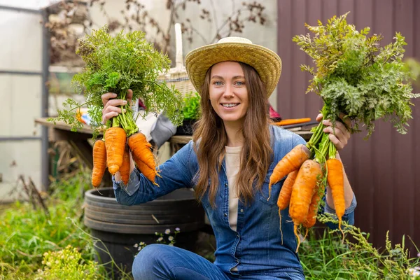 一个快乐的女农场主在镜头前展示新鲜的大有机胡萝卜的蜡像 — 图库照片