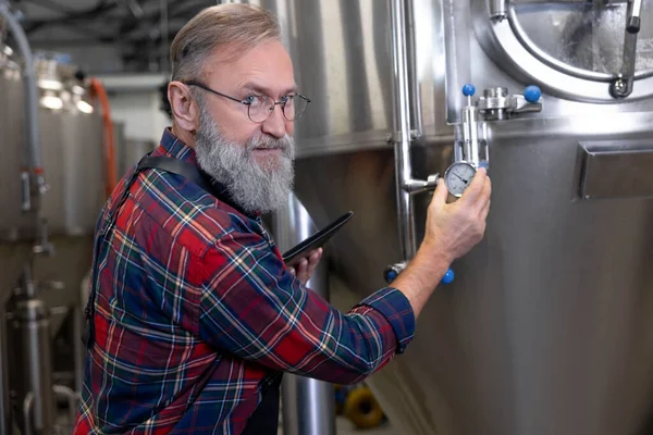 仕事の監督 タンク内の圧力をビールでコントロールする醸造労働者 — ストック写真