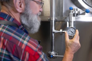 İş denetimi. Bira fabrikası işçisi tanklardaki basıncı birayla kontrol ediyor.