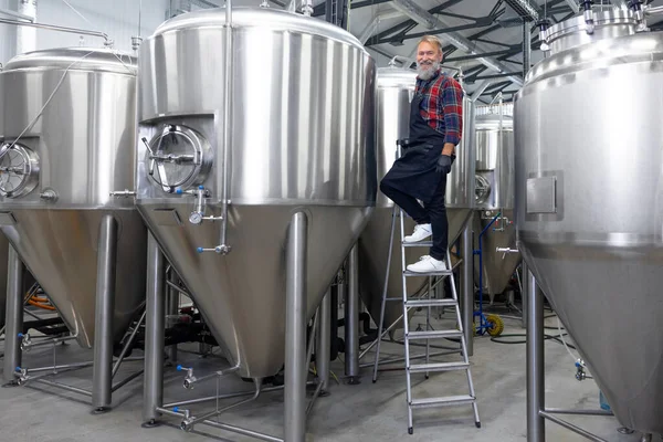 Good result. Factory worker checking the tanks with beer and looking satisfied with the result
