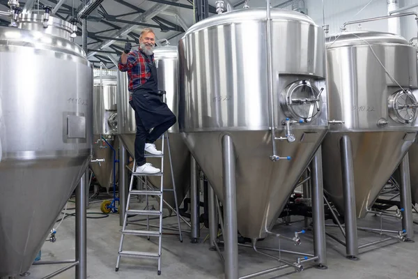 Good result. Factory worker checking the tanks with beer and looking satisfied with the result