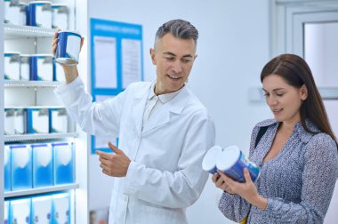 Good choice. Male pharmacist helping young woman to choose infant milk