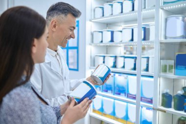 Good choice. Male pharmacist helping young woman to choose infant milk