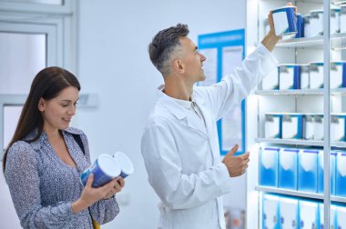 Good choice. Male pharmacist helping young woman to choose infant milk