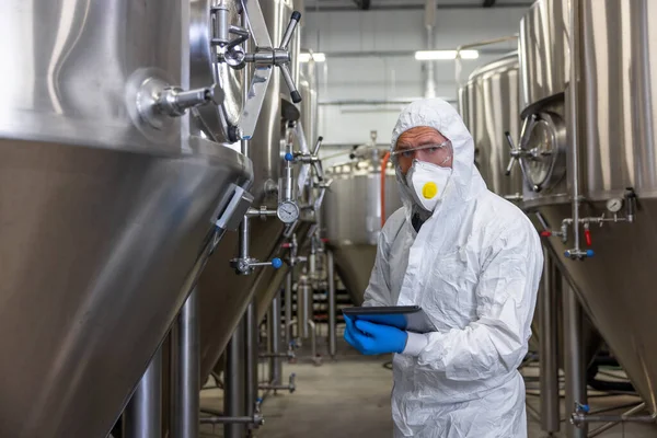 Serious Brewery Technologist Protective Mask Standing Fermentation Tanks Tablet Computer — Fotografia de Stock